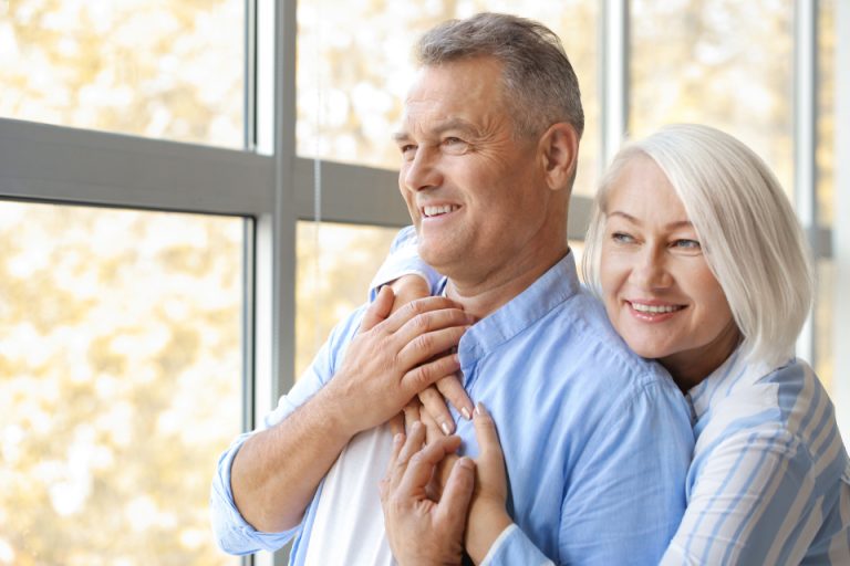 An older couple at home beside a window